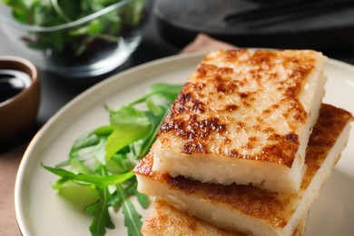 Delicious turnip cake with arugula served on table, closeup
