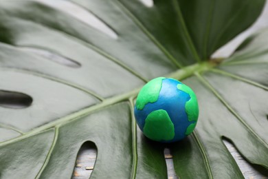 Happy Earth Day. Planet made of plasticine on green leaf, space for text