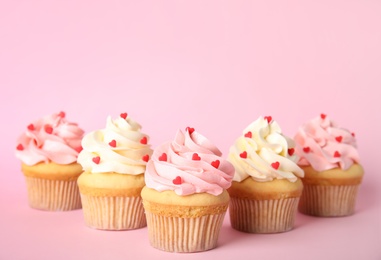 Tasty cupcakes with heart shaped sprinkles on pink background. Valentine's Day celebration