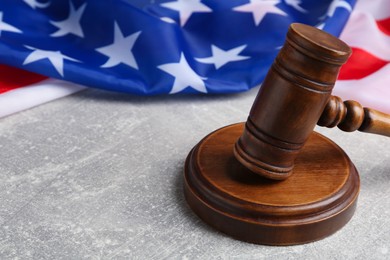 Photo of Judge's gavel and American flag on light grey table, closeup. Space for text