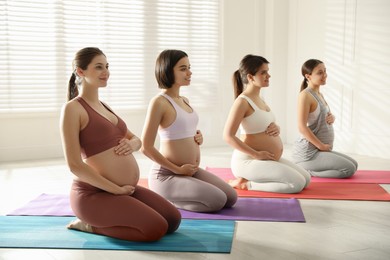Group of pregnant women practicing yoga in gym
