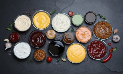 Many different sauces on black table, flat lay