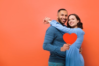 Photo of Lovely couple with paper heart on red background, space for text. Valentine's day celebration