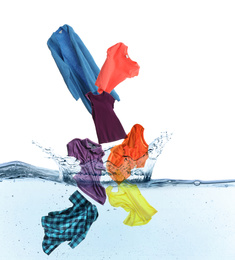 Different clothes falling into water against white background
