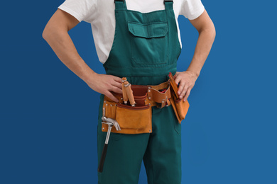 Photo of Carpenter with tool belt on blue background, closeup