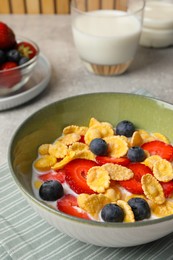 Corn flakes with berries in bowl served on grey table, closeup