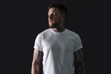 Photo of Handsome hipster man with tattoos on black background