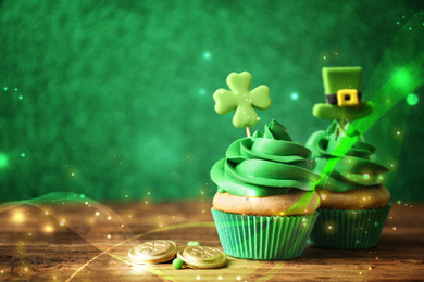 Decorated cupcakes and coins on wooden table, space for text. St. Patrick's Day celebration