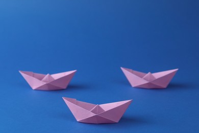 Handmade violet paper boats on blue background. Origami art