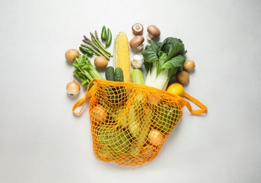 Photo of Fresh vegetables in eco mesh bag on white background, flat lay