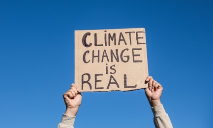 Young woman with poster protesting against climate change outdoors, closeup