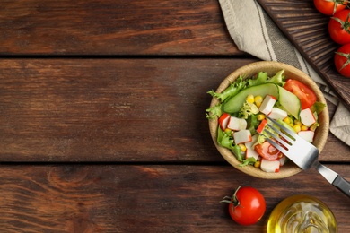 Crab stick salad with tomatoes and lettuce on wooden table, flat lay. Space for text