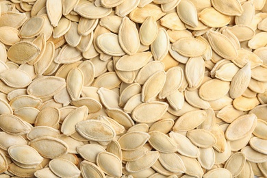 Raw unpeeled pumpkin seeds as background, top view