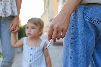 Woman smoking cigarette in public place outdoors, closeup. Don't smoke near kids