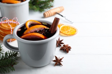 Aromatic mulled wine and ingredients on white wooden table. Space for text
