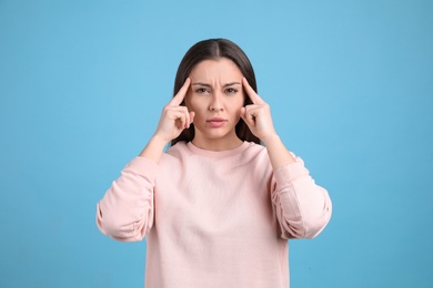 Portrait of stressed young woman on light blue background