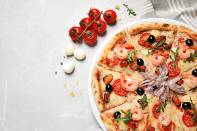 Tasty pizza with seafood and ingredients on light grey marble table, flat lay