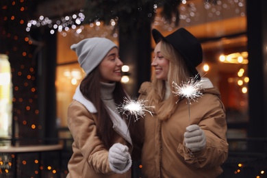 Happy young women with sparklers at winter fair