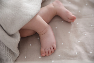 Photo of Cute little baby lying in bed, closeup of feet. Bedtime