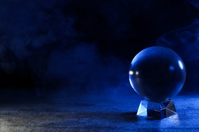 Magic crystal ball on table against dark background, space for text. Making predictions