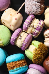 Photo of Delicious colorful macarons on black background, flat lay