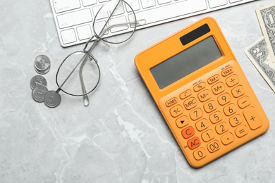 Calculator, glasses, keyboard and money on marble table, flat lay. Tax accounting