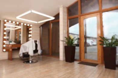 Blurred view of hairdressing salon with large mirror and chair