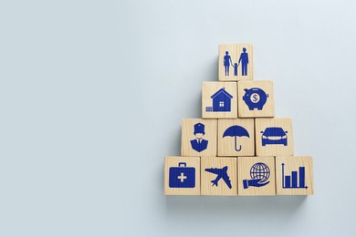 Wooden cubes with different icons on light background, flat lay. Insurance concept