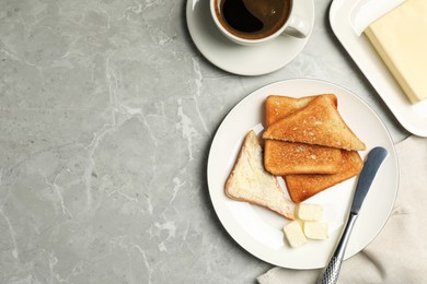 Photo of Tasty toasts with butter served on grey marble table, flat lay. Space for text