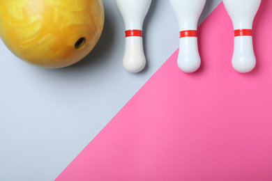 Bowling ball and pins on color background, flat lay. Space for text