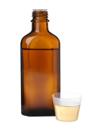 Photo of Bottle with measuring cup of syrup on white background. Cough and cold medicine