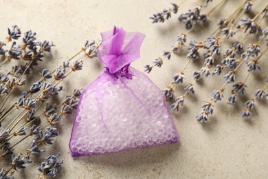 Scented sachet with aroma beads and dried lavender on grey table, flat lay