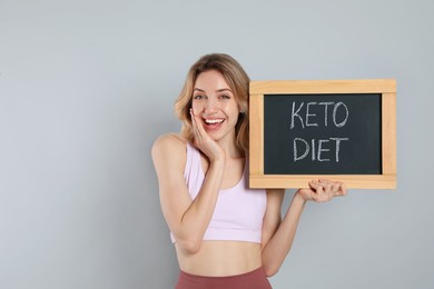 Woman holding blackboard with phrase Keto Diet on grey background