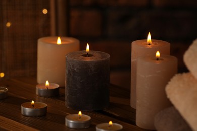Photo of Spa composition with burning candles on wooden table in wellness center, closeup