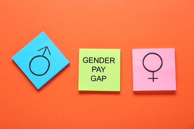 Photo of Gender pay gap. Notes with male and female symbols on orange background, flat lay
