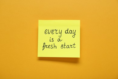 Photo of Note with phrase Every Day Is A Fresh Start on orange background, top view. Motivational quote
