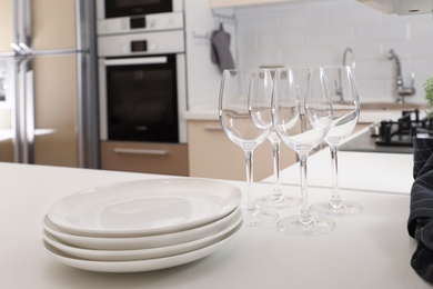 Stack of clean dishes and glasses on table in kitchen
