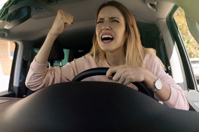 Stressed angry woman in driver's seat of modern car, view through windshield