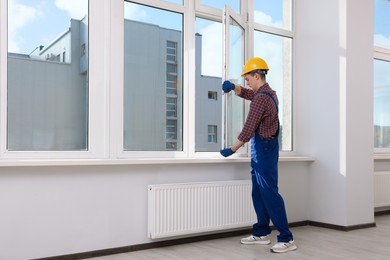 Worker in uniform installing plastic window indoors