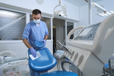 Professional dentist in uniform and medical mask cleaning workplace indoors