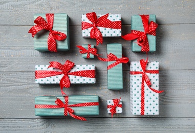Christmas gift boxes with red bows on grey wooden background, flat lay