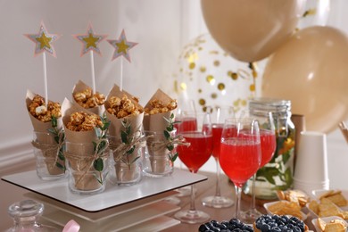 Delicious party treats and drinks on wooden table indoors
