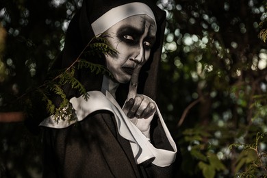 Portrait of scary devilish nun near tree outdoors. Halloween party look