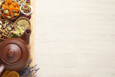 Clay teapot and different dried herbs on white wooden table, top view. Space for text