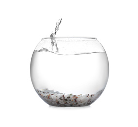 Splash of water in round fish bowl with decorative pebbles on white background