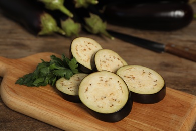 Cut raw ripe eggplant and parsley on wooden board