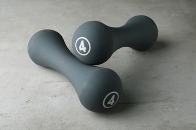 Grey rubber coated dumbbells on light table