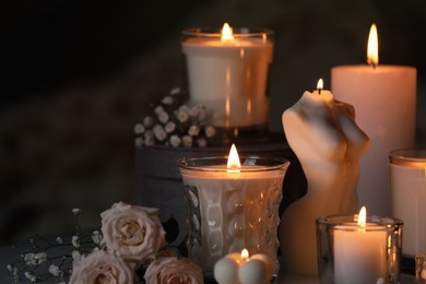 Beautiful burning candles and flowers on blurred background