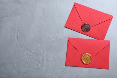 Red envelopes with wax seals on grey background, flat lay. Space for text