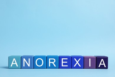 Word Anorexia made of colorful cubes with letters on light blue background